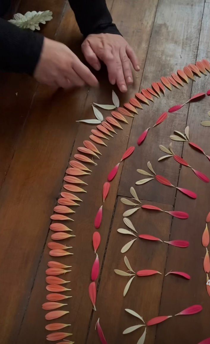 Manos componiendo un mandala de hojas y pétalos