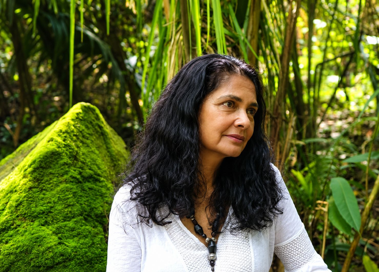 Silvia Ochoa en el bosque amazónico, junto a una roca cubierta de musgo