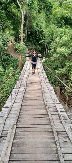 Silvia Ochoa caminando sobre un puente colgante en la Amazonía
